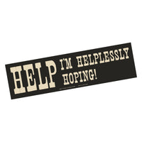 Bumper sticker with text 'HELP I'M HELPLESSLY HOPING!' on a black background