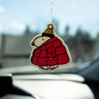 Car air freshener shaped like a cartoon character in a red coat hanging from a car's rearview mirror.