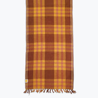 Brown and pink plaid table runner with fringed edges.