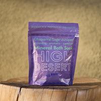 Purple package of High Desert Mineral Bath Soak on a wooden surface with a beige background