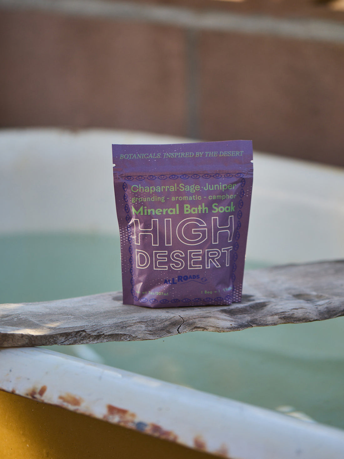Purple packet of High Desert Mineral Bath Soak on a wooden surface with a blurred background