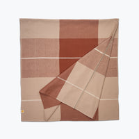 Folded checkered tablecloth with brown and beige colors on a white background