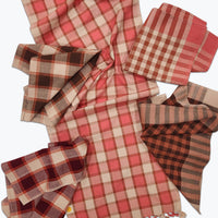 Red and beige checkered tablecloth with napkins on a white background