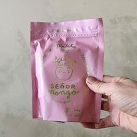 Hand holding a pink package labeled 'Señor Mango' against a neutral background