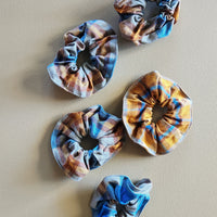 Five patterned scrunchies on a beige background