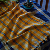 Yellow and blue checkered cloth on a table with a candle and decorative items.