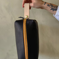 black leather dopp toiletry kit with yellow zipper.