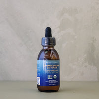 Bottle of organic golden castor oil on a neutral background
