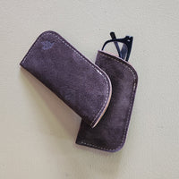 Brown suede glasses case with a pair of glasses on a light gray background