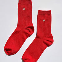 Pair of red socks with heart details on a light gray background