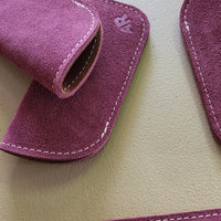 Close-up of purple suede eyeglass cases on a beige surface