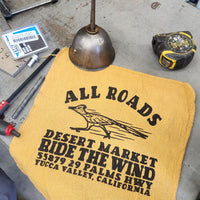 Yellow towel with text and logo on a workshop surface with tools.