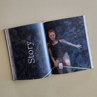 Open book with a dark, artistic cover featuring a person and the word 'Story' on a beige background.
