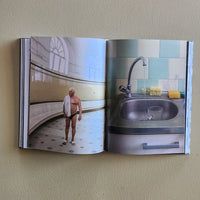 Open book showing a bathroom scene with a man standing in front of a sink.
