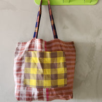 Plaid bag hanging on a green hook against a gray wall