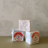 Three stacked soap bars with visible branding on a neutral background