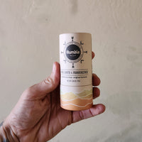 Hand holding a cylindrical product with 'Humble' branding against a plain background