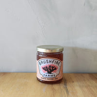 a jar of peach pepper jam made in texas.