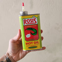A hand holidng a can of Rosi's Hot Oil