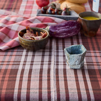 Table setting with checkered tablecloth, bowls, and fruits on a rustic background