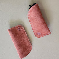 Two rust suede eyeglass cases on a light gray background