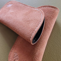 tan suede eyeglass case on a green surface