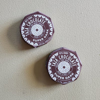 Two Taza Chocolate super dark chocolate bars on a light gray background