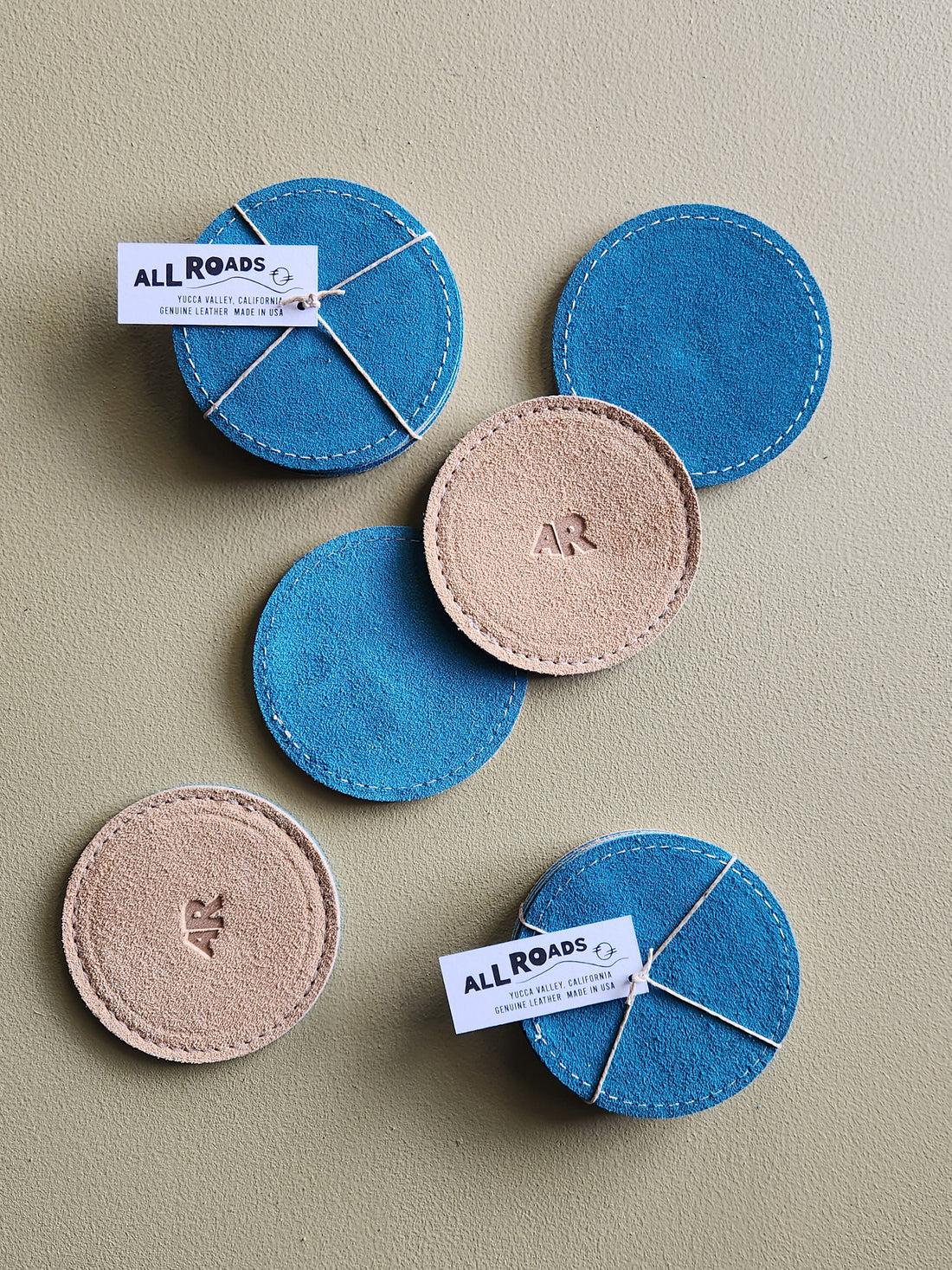 Set of 4 suede coasters, 1 side teal the other side tan with an AR brand.