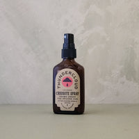 Bottle of creosote Spray with 'Thundercloud' label on a neutral background