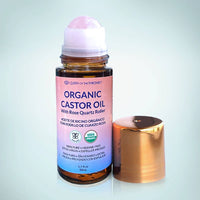 Organic castor oil bottle with rose quartz roller on a light gray background