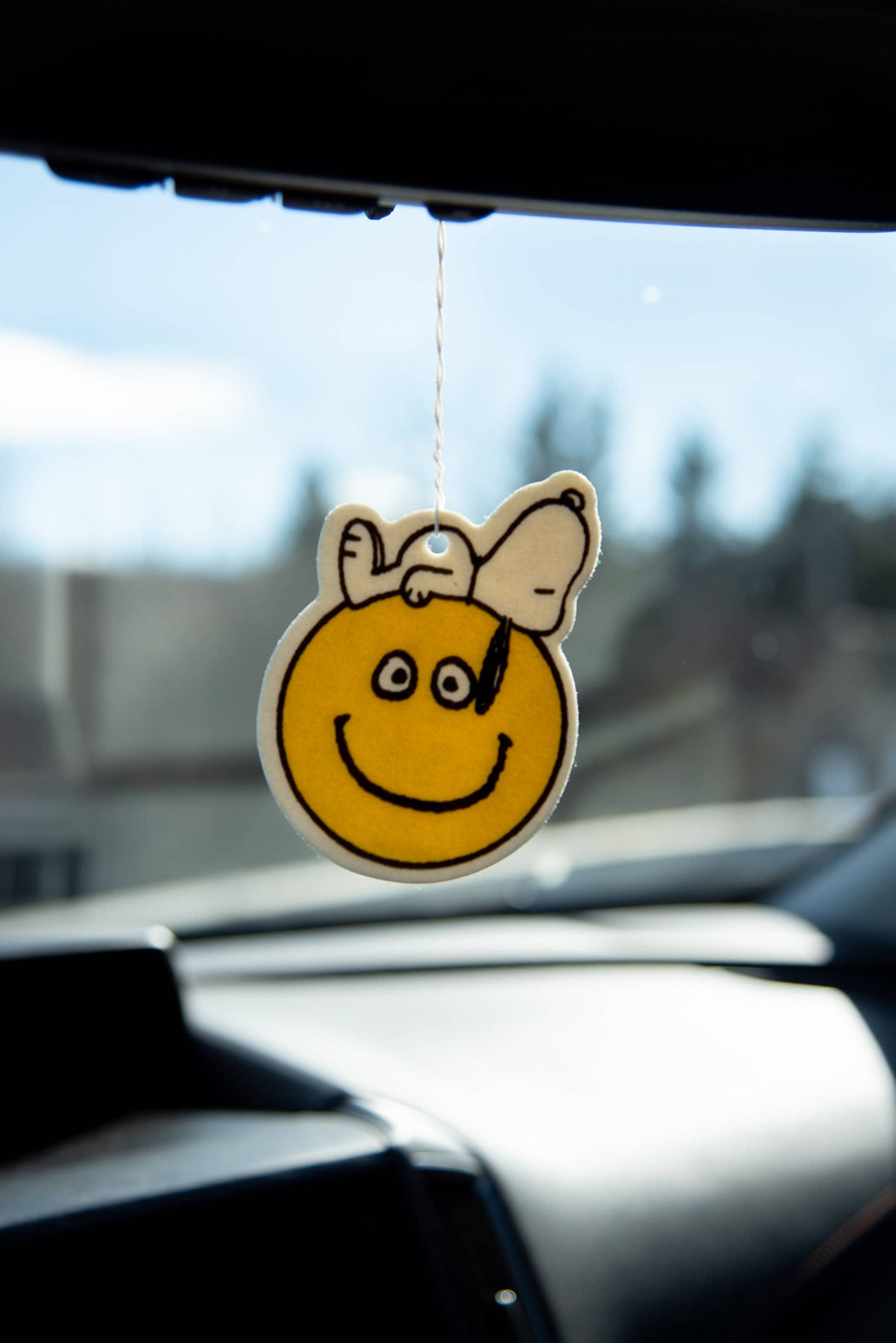Smiley face air freshener hanging from a car&