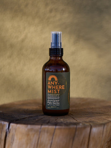 Brown spray bottle labeled 'Anywhere Mist' on a wooden surface with a brown background