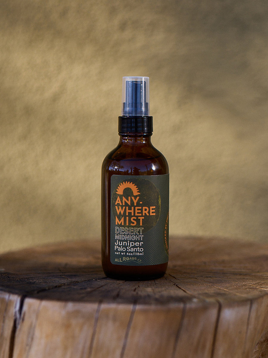 Brown spray bottle labeled 'Anywhere Mist' on a wooden surface with a brown background