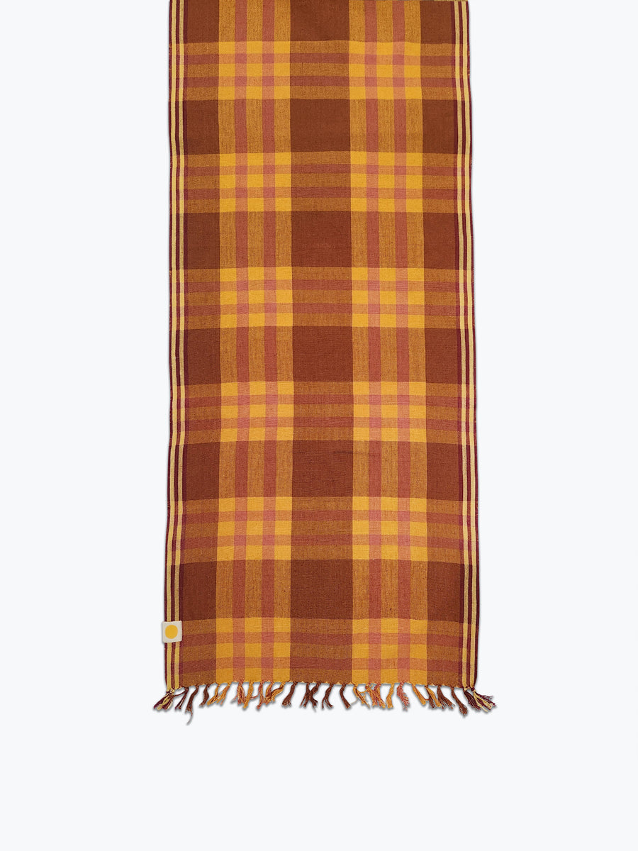 Brown and pink plaid table runner with fringed edges. 