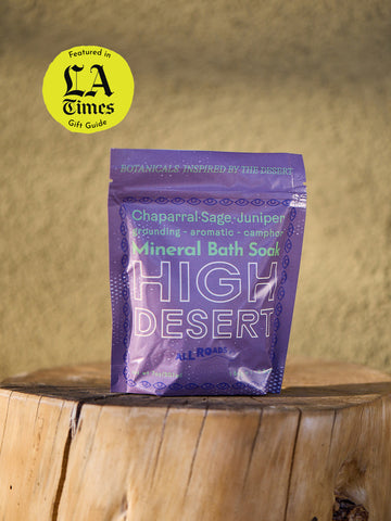 Purple package of High Desert Mineral Bath Soak on a wooden surface with a blurred background