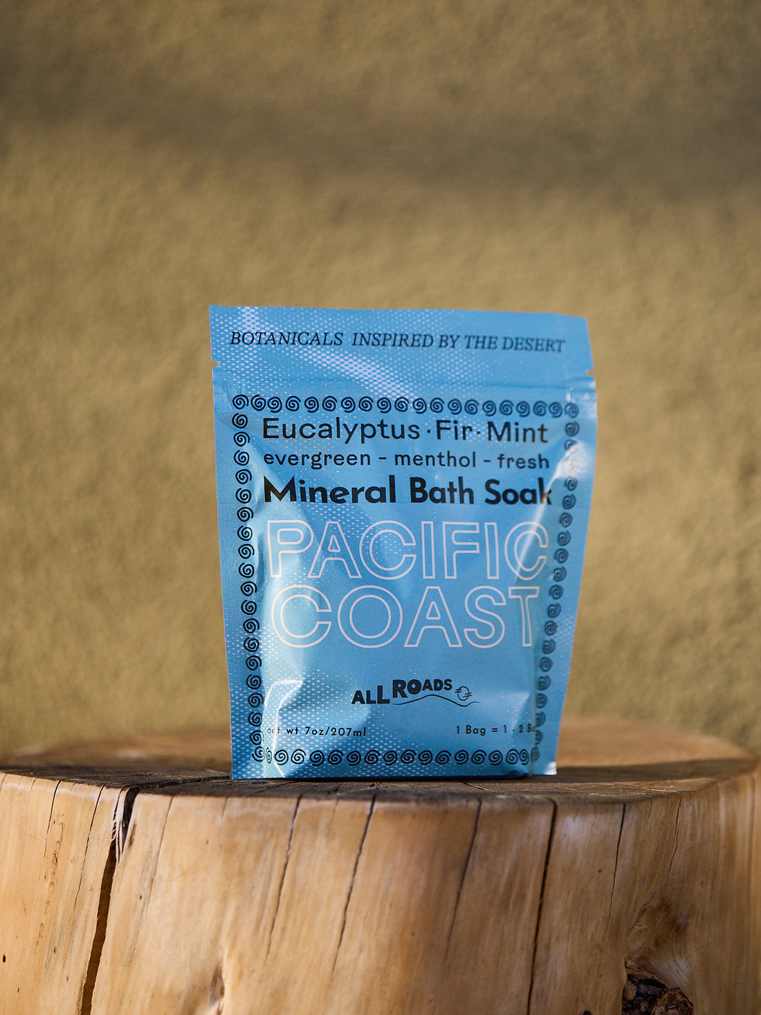Blue package of Pacific Coast Mineral Bath Soap on a wooden surface with a blurred natural background