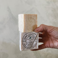 Hand holding a block of soap with branding on a light background