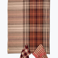Plaid blanket with a pattern of red, brown, and beige colors on a white background.