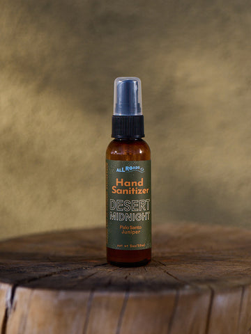 Hand sanitizer bottle labeled 'Desert Midnight' on a wooden surface with a brown background