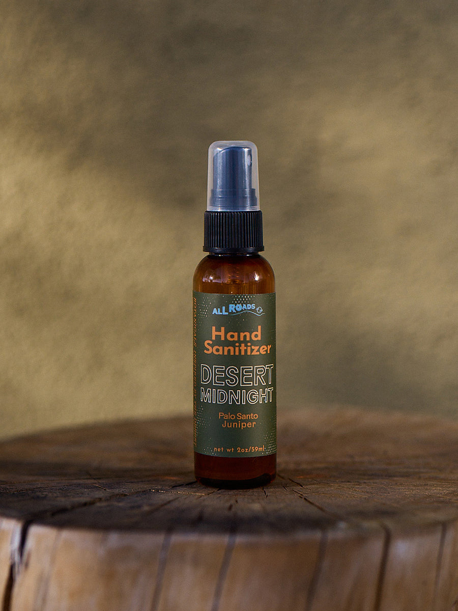Hand sanitizer bottle labeled 'Desert Midnight' on a wooden surface with a brown background