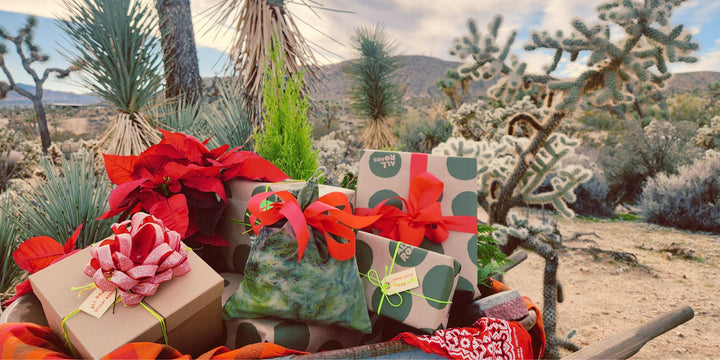 Gifts wrapped in red and green paper with ribbons in a desert setting.