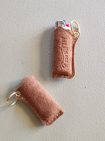 Two brown leather keychains with key rings on a light gray background