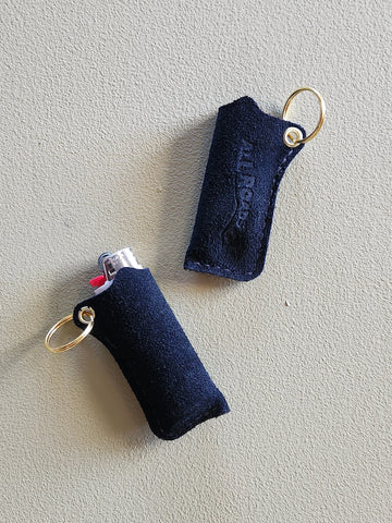 Two black swuede keychain pouches with gold loops on a light gray background