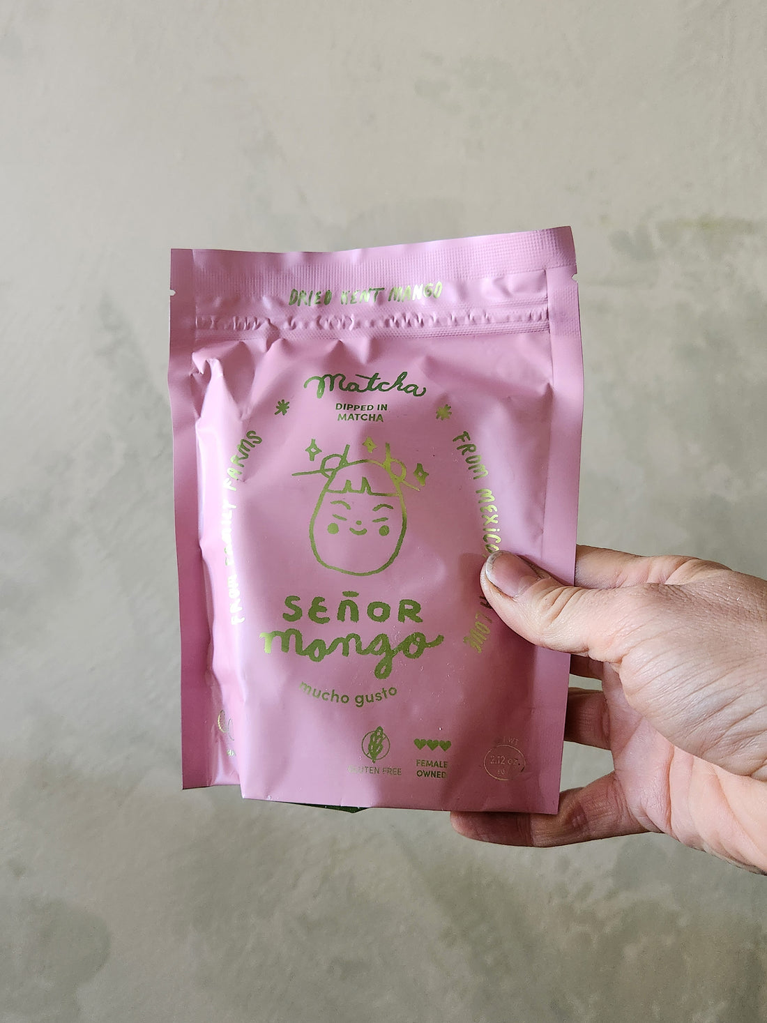 Hand holding a pink package labeled &