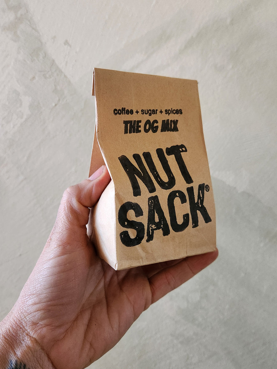 Hand holding a 'Nut Sack' package with text on a neutral background