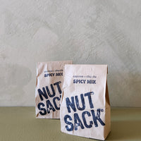Two 'Nut Sack' spicy mix packages on a textured surface with a neutral background