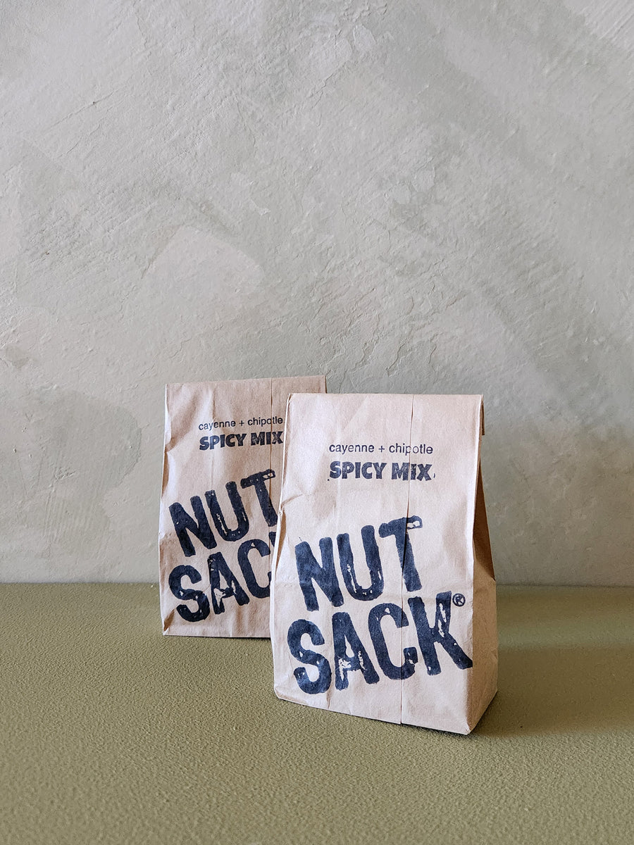 Two 'Nut Sack' spicy mix packages on a textured surface with a neutral background