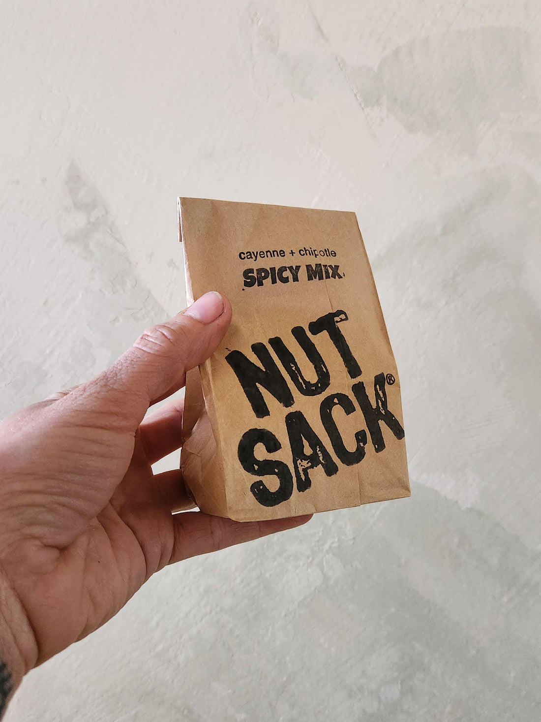Hand holding a small brown paper bag labeled &