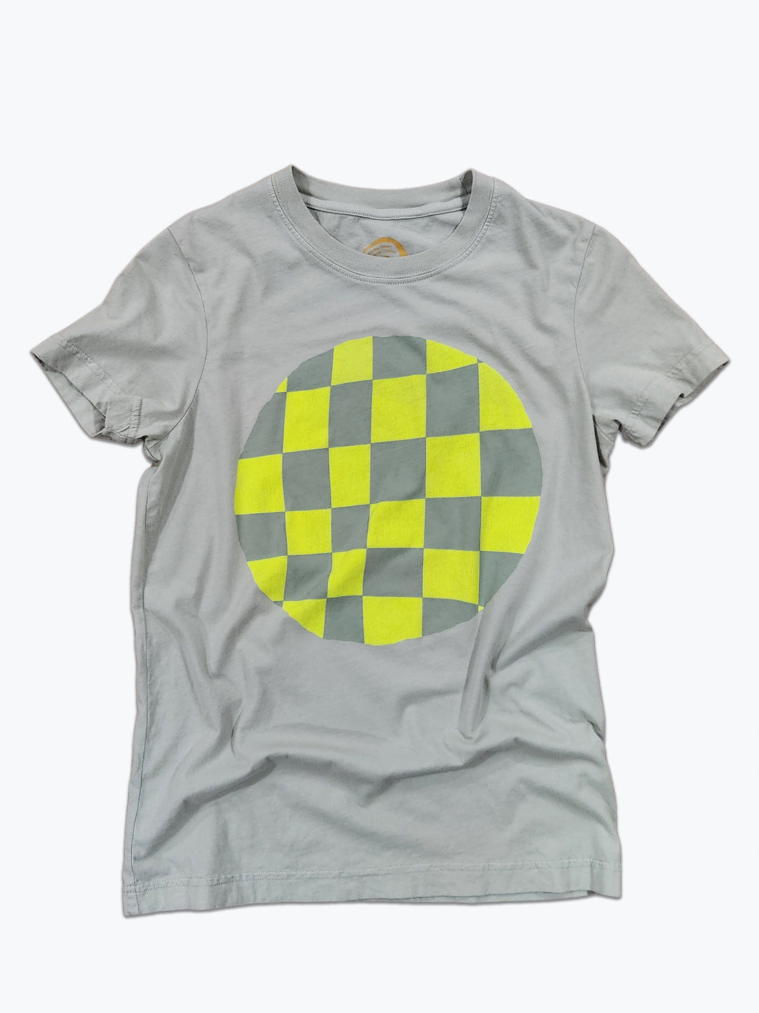 A light green short-sleeve crewneck t-shirt featuring a large circular graphic on the chest with a yellow and sage green checkerboard pattern.