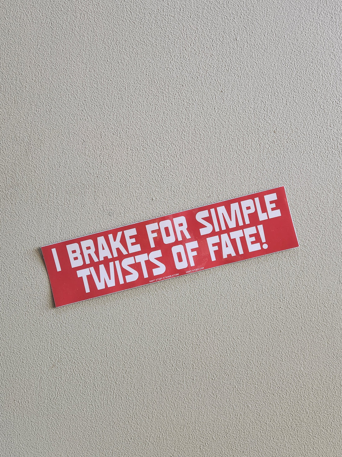 Red bumper sticker with white text on a gray background